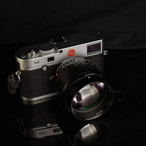 This is an image of a Leica M-series camera with the 7artisans 75mm f/1.25 lens attached against a nearly all-black background.