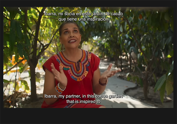 This image, which has been imported into Adobe Premiere Pro and has white captions at the top and on the bottom of the photo, shows a woman in a red dress looking up with her hands held out.]] 