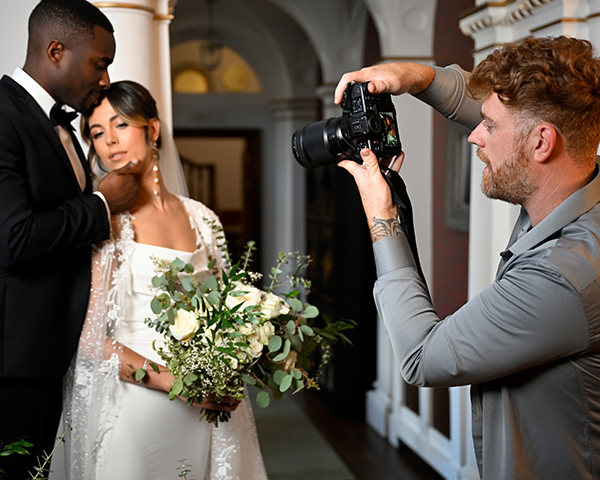 A photographer is shooting a bride and groom using a Nikon camera with a Nikon Nikkor Z 35mm F/1.2 S lens.